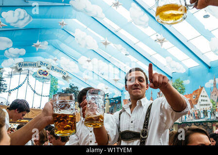 Jeune homme en pantalon de cuir debout sur les bancs de la bière Oktoberfest célébrer dans la tente à bière Banque D'Images