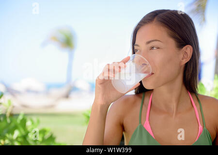 Jeune femme à boire de l'eau fraîche ou de jus de citron vert à la plage. Femelle est à l'écart tout en étant assis au restaurant en plein air. Bel'est avoir boisson saine pendant les vacances d'été. Banque D'Images