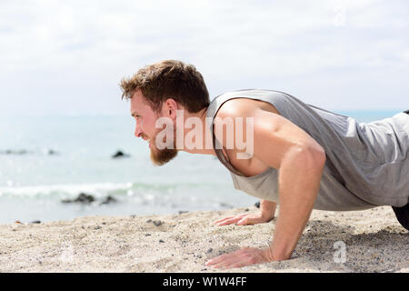 Homme remise en forme push-up faire l'exercice sur la plage. Portrait de monter son travail guy les muscles des bras et du corps avec des exercices de base pushup sur plage de sable fin. Banque D'Images