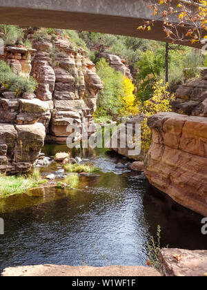 Rivière qui coule sous un pont avec les roches rouges en Slide Rock State Park à l'extérieur Arizona Sedona Banque D'Images