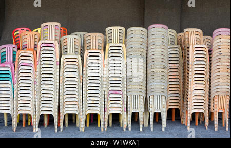 Beaucoup de chaises ! Blanc, rose et orange plastique chiars empilés Banque D'Images