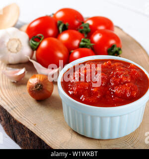 Sauce tomate à l'ail, le basilic et les épices dans un bol blanc sur fond de bois Banque D'Images