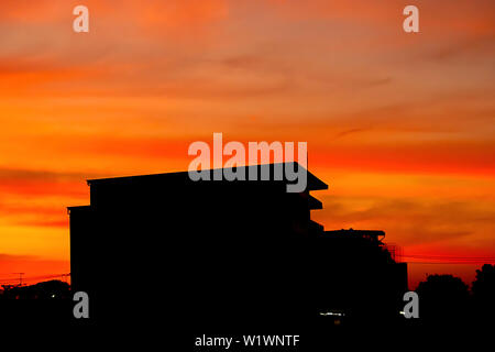 Belle Lumière du coucher de soleil avec des nuages dans le ciel la réflexion derrière le bâtiment. Banque D'Images