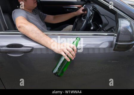 Ne buvez pas de concept d'entraînement, jeune homme ivre de boire une bouteille de bière ou d'alcool au cours de conduire la voiture dangereusement. Banque D'Images