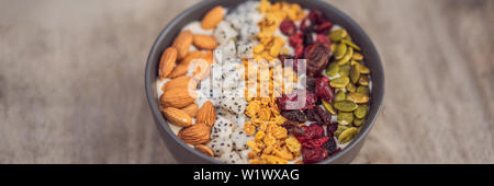 Smoothies mangue bol avec l'amande, fruit du dragon, cerises séchées, graines de citrouille et granola bannière sur fond de bois, format long Banque D'Images