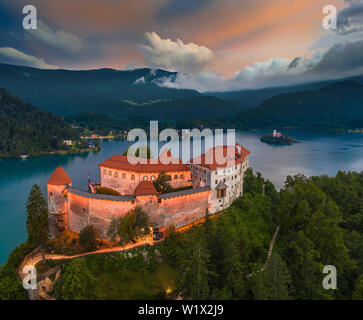 Bled, Slovénie - vue aérienne du château de Bled illuminé magnifique (Blejski Grad) avec l'église de l'assomption de Maria et les Alpes Juliennes au background Banque D'Images