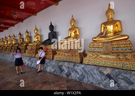 Deux jeunes dans les écoles Les écoles tenues prendre en face d'autoportraits à la rangée de statues de Bouddha du Wat Po (PHO), Bangkok, Thaïlande Banque D'Images