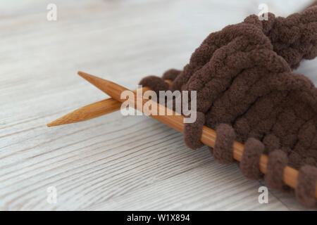 Les aiguilles à tricoter en bois et de tricot de laine marron épais. Close-up. Utiliser comme une démonstration de l'artisanat féminin Banque D'Images