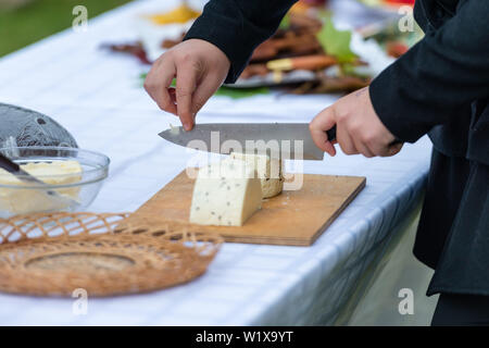 Partager le travailleur du fromage. Close up of hands coupé au couteau fromage - Droit Banque D'Images