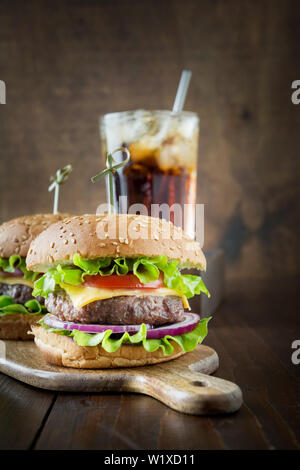 Les deux hamburgers avec légumes avec cola sur planche de bois. Fête de l'été. Close up. Orientation verticale. Banque D'Images