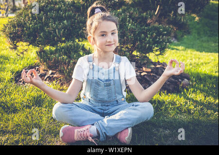 Jeune fille pratique le yoga et médite dans la position du lotus dans le jardin japonais. Calme et heureuse adolescent Banque D'Images