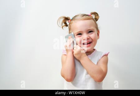 Portrait de la petite fille est positif que de parler sur un téléphone Banque D'Images