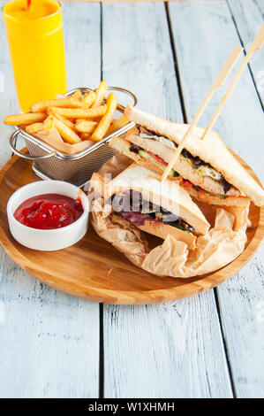 Deux clubs sandwichs et frites sur une plaque de bois. Banque D'Images