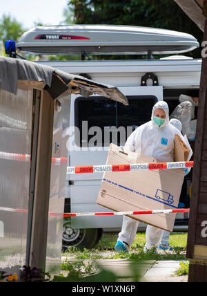 04 juillet 2019, en Rhénanie du Nord-Westphalie, Lügde : Au cours des fouilles sur un terrain sur le site de camping à Lügde, des policiers transporter plusieurs boîtes dans la cabane camping d'un nouveau suspect. La police recherche le camping de Lügde à nouveau dans le cadre de l'abus au centuple. À Detmold, le processus se poursuit en parallèle. Photo : Guido Kirchner/dpa Banque D'Images