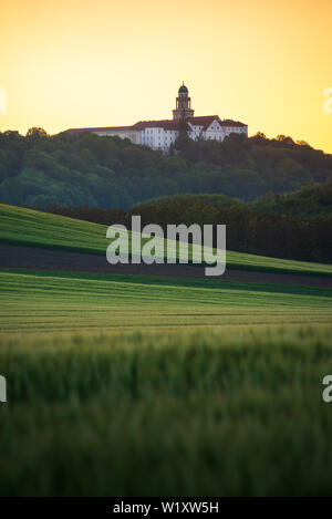 Pannonhalma Archabbey avec champ de blé au printemps l'heure du coucher de soleil. Banque D'Images