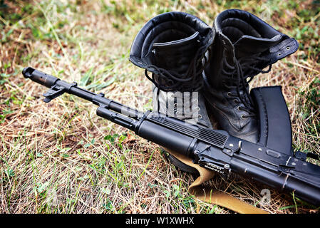 Bottines de soldat et un fusil d'assaut Kalachnikov close-up Banque D'Images