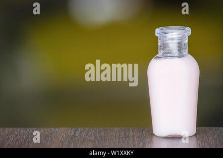 Petite bouteille de gel douche sur une table en bois, l'arrière-plan flou. Banque D'Images