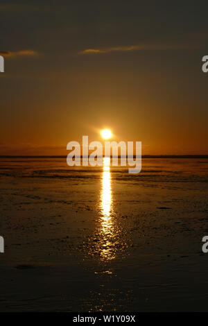 Coucher du soleil sur la mer du Nord, directement sur la plage. Ciel Orange et marée basse. Banque D'Images