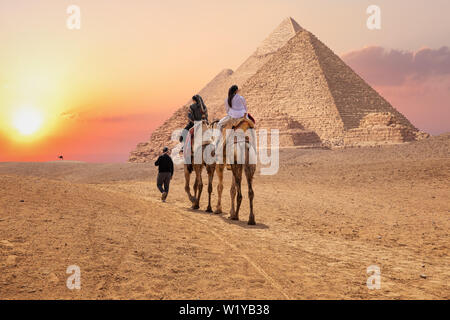 Les touristes sur les chameaux près les grandes pyramides de Gizeh, en Egypte. Banque D'Images