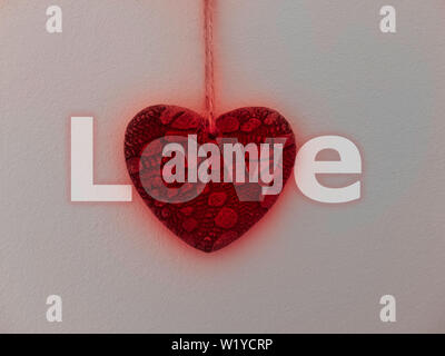 Coeur de pierre rougeoyants rouges accrochés au mur blanc recouvert de plâtre avec message d'amour. Banque D'Images