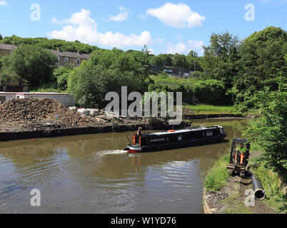 Bateau ou yacht "étroit canal Arlequins" fait un virage serré comme il passe Finsley Gate quai du canal de Leeds et Liverpool à Burnley lors d'une journée ensoleillée. Banque D'Images