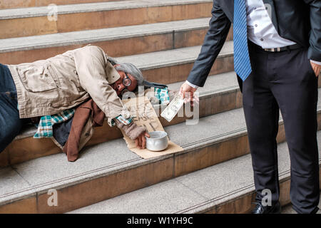 Businessman giving donation dollar cash avec coin nuit vieille personne sans-abri Banque D'Images