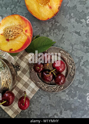 La vue étonnante de pêches et de cerises sur la table. Les fruits juteux, lumineuse - les pêches et les cerises. Banque D'Images