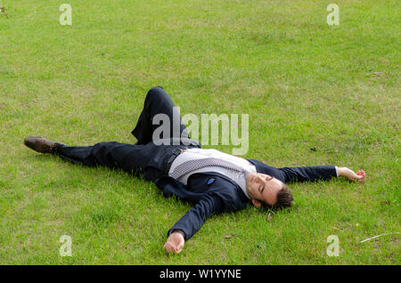 Portrait of handsome businessman relaxing outdoor dans l'herbe verte au travail, porter une cravate, tailleur, chemise blanche, blanc, de repos d'Europe Banque D'Images