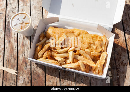 La traditionnel fish and chips dans une boîte sur une table en bois. Banque D'Images