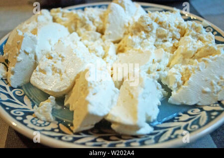 Home-made en tranches de fromage de brebis sur une plaque bleue avec un beau motif sur la table de fête Banque D'Images