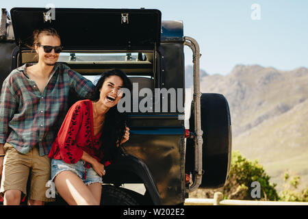 Belle femme debout avec son petit ami et rire. Couple standing penchant à la voiture à l'extérieur et à heureux. Banque D'Images