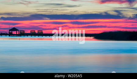 Coucher du soleil Outer Banks de la Caroline du Nord - juste après que sun a traversé l'horizon sur un jour nuageux. Marais et zones humides avec gazebo sur quai à distance. Banque D'Images