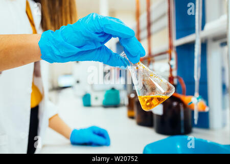 Femme ou femme les mains dans les gants de tenir les mains en tube de test produit test de l'expérience de la chimie moderne et de la recherche en laboratoire de chimie. Banque D'Images