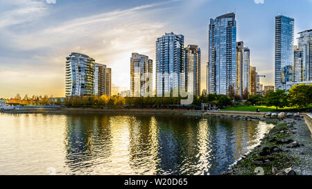 Comme le coucher du soleil le soleil se couche derrière les gratte-ciel modernes qui tapissent l'horizon de Yaletown le long de False Creek Inlet de Vancouver, British Columbia, Canada Banque D'Images