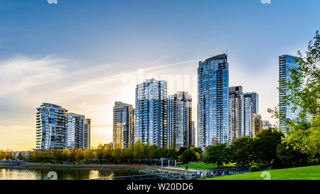 Comme le coucher du soleil le soleil se couche derrière les gratte-ciel modernes qui tapissent l'horizon de Yaletown le long de False Creek Inlet de Vancouver, British Columbia, Canada Banque D'Images