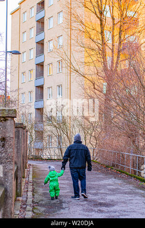 Un père tient la main de son Fils comme ils faire une promenade le long d'un chemin à Turku, Finlande en hiver. Banque D'Images