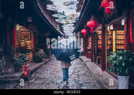 Girl with umbrella walking sur Lijiang City street Banque D'Images