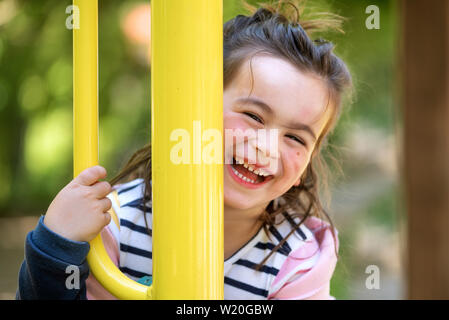 Cute girl enjoying sur aire de jeux dans le parc en été . Banque D'Images