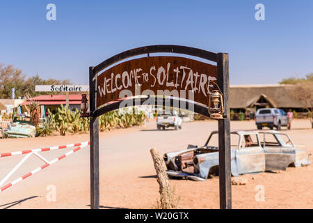 Welcome sign at Solitaire, Sesriem, Namibie avec de vieux wagons rouillés derrière. Banque D'Images