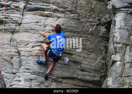 Un jeune grimpeur travaille son chemin d'une falaise sur le rebord du sentier du printemps à Pilot Mountain State Park en Caroline du Nord. Banque D'Images