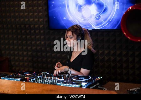 Party Time avec blonde female DJ dans un night club de musique. Le mélange de musique électro et de l'utilisation des écouteurs. Banque D'Images