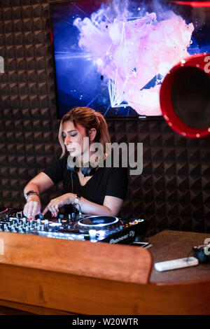 Party Time avec blonde female DJ dans un night club de musique. Le mélange de musique électro et de l'utilisation des écouteurs. Banque D'Images