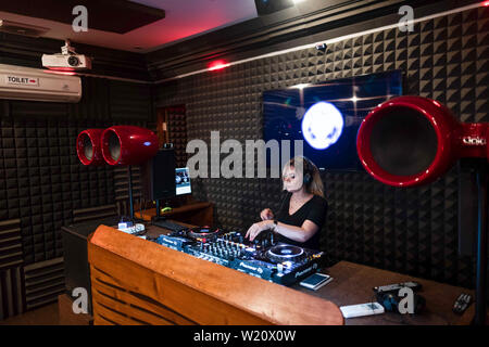 Femme blonde jouant DJ et mixage musique de danse moderne dans un club lors d'une soirée house party Banque D'Images