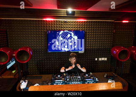 Femme blonde jouant DJ et mixage musique de danse moderne dans un club lors d'une soirée house party Banque D'Images
