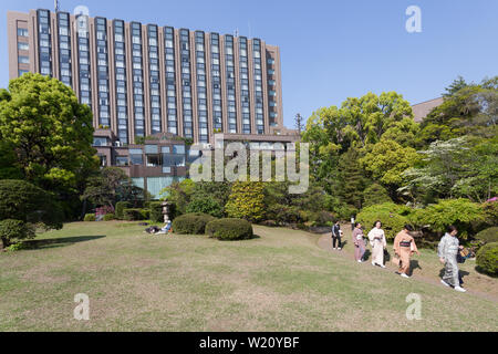 Les femmes, portant un kimono, traversent le jardin de Ōkuma sur le campus de l'université de Waseda, bâtiment Regha Royal Hotel derrière. Shinjuku, Tokyo, Japon Banque D'Images