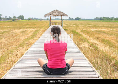 Femme assise sur un pont en bois avec une cabane en bambou dans les rizières. Banque D'Images