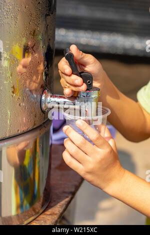 Garçon à la main tenant le verre avec l'eau du refroidisseur d'eau. Banque D'Images