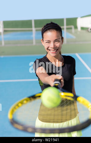 Raquette de tennis girl holding et la balle sur le court. Athlète sport femme asiatique montrant les appareils de sport sur la terrasse extérieure d'entraînement de fitness club. Personne souriante ethniques attrayant. Banque D'Images