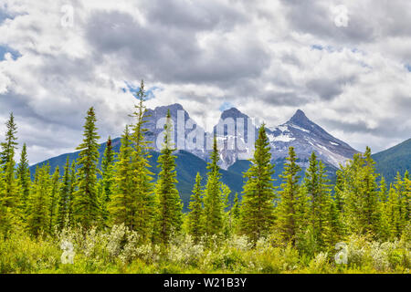 Canmore célèbre Trois Sœurs des pics de montagne dans le sud de la gamme Banff Canadian Rockies nuageux sur un matin de printemps. Le trio des pics sont na Banque D'Images