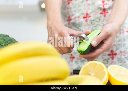 La cuisson des aliments sains femme dans sa cuisine, elle épluche un concombre frais sur la planche à découper Banque D'Images